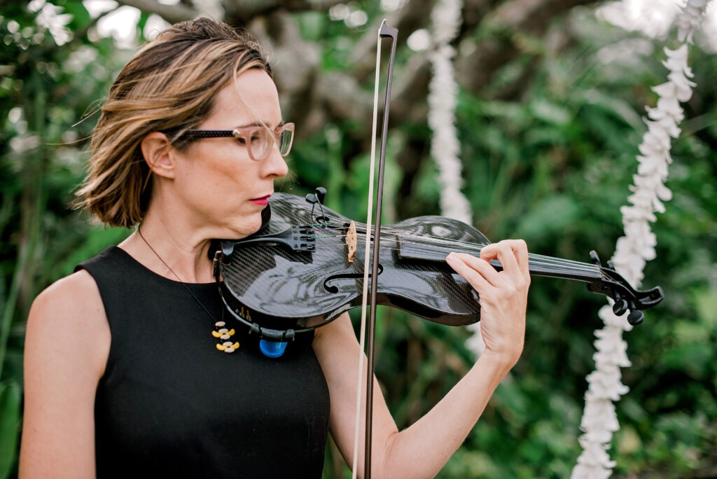 Violinist performing live music at a romantic beach wedding ceremony.