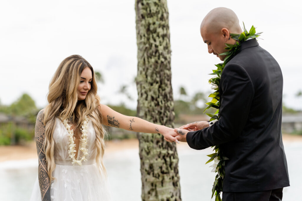 Intimate moment as the groom slips the ring onto his bride’s hand in Maui