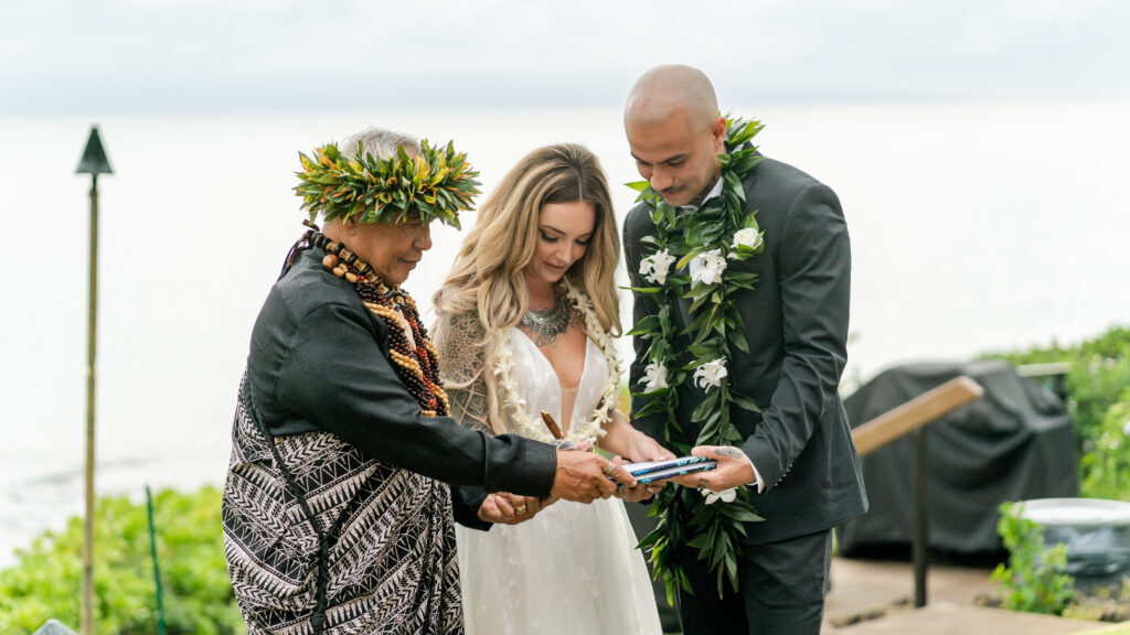 Bride and groom signing their wedding certificate with the officiant in Maui
