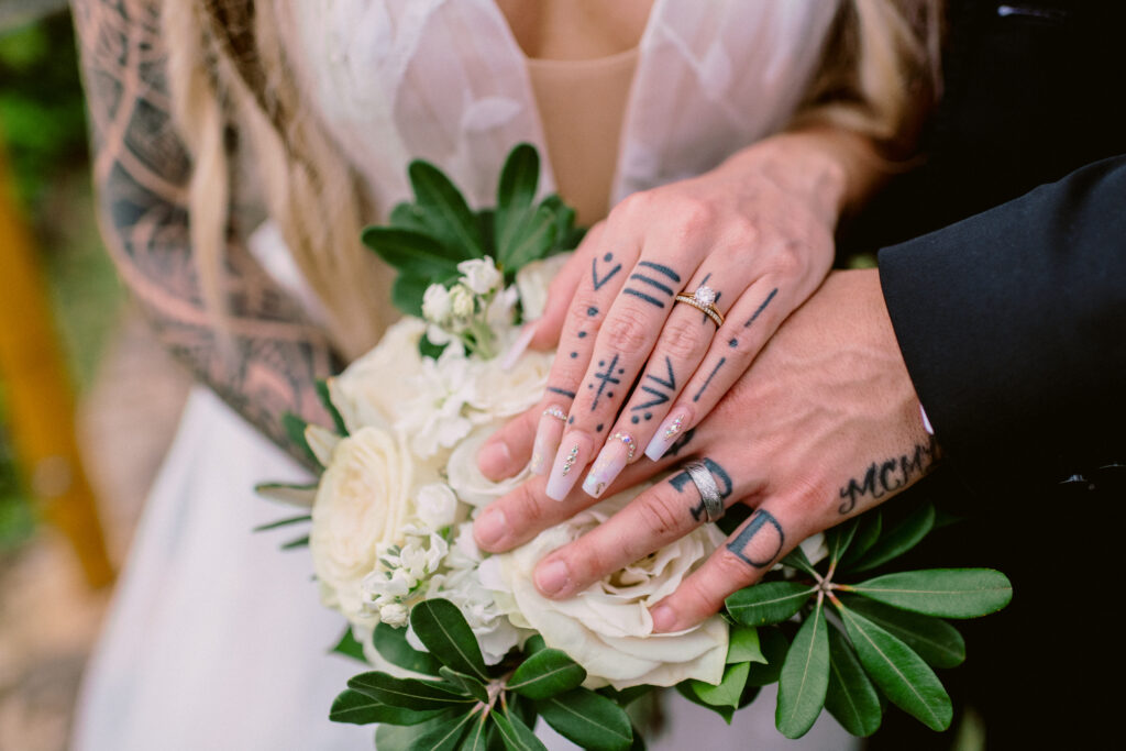 Detail shot of bride and groom holding hands showing wedding rings