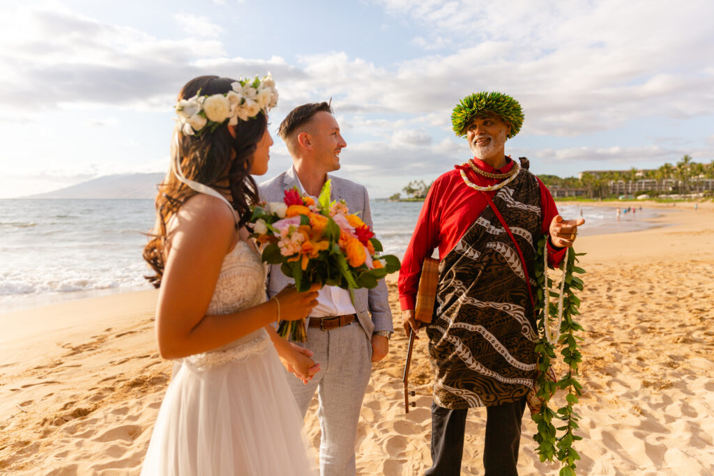 Couple listening to their officiant during an intimate Maui beach elopement