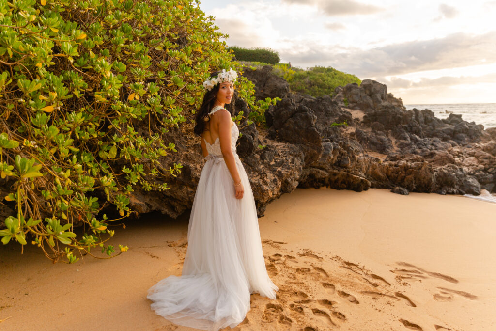 Bride in a flowing dress standing on a Maui beach during elopement