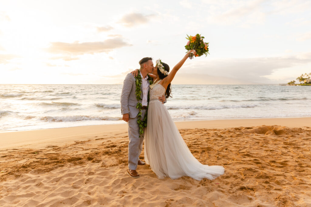 Eloping couple sharing a kiss on a Maui shoreline