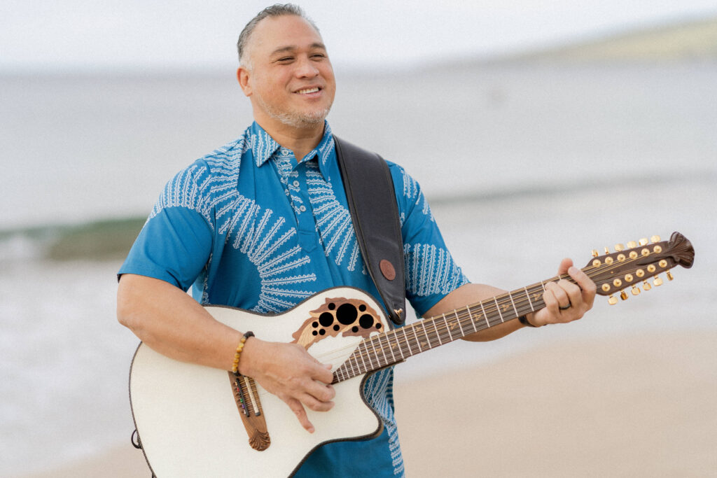 Guitarist playing acoustic wedding songs on the beach for a couple’s ceremony.
