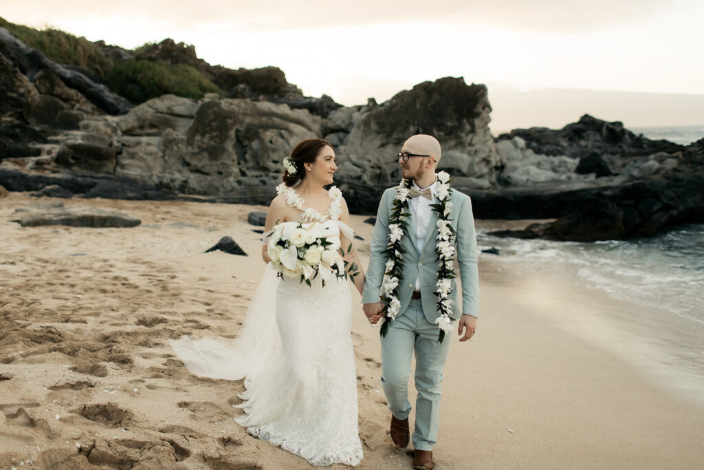 Couple walking hand in hand happily on their wedding day at a Maui beach