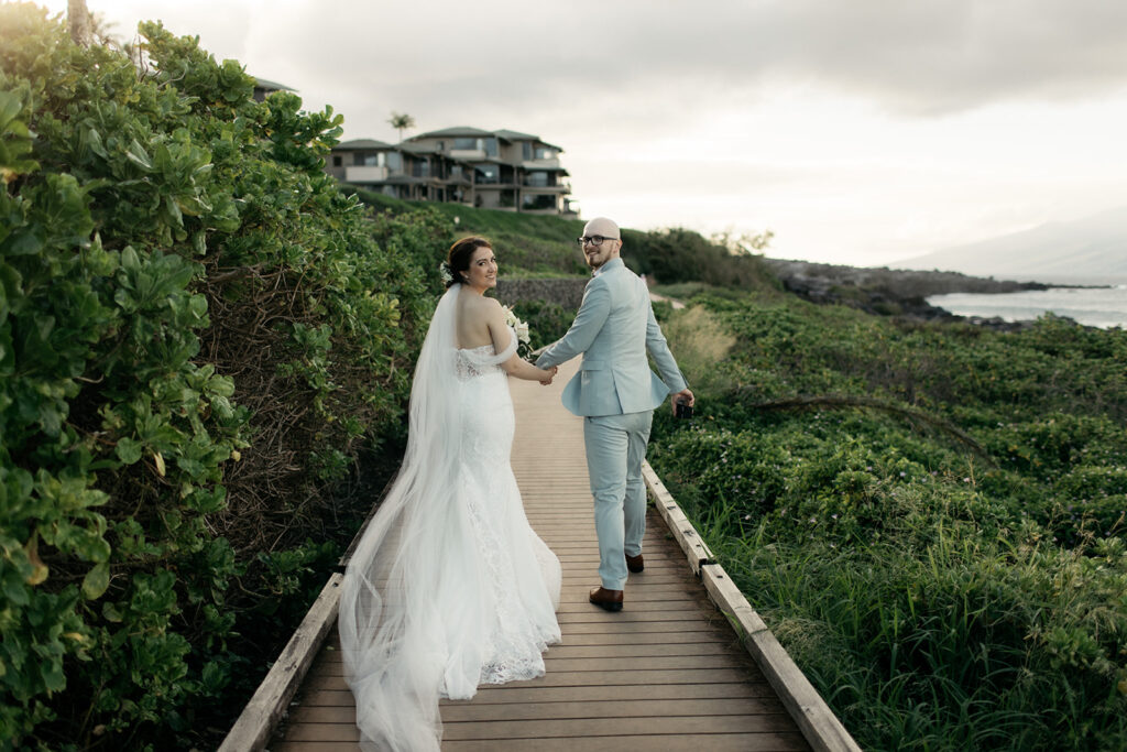 Couple walking hand in hand happily on their wedding day at a Maui beach