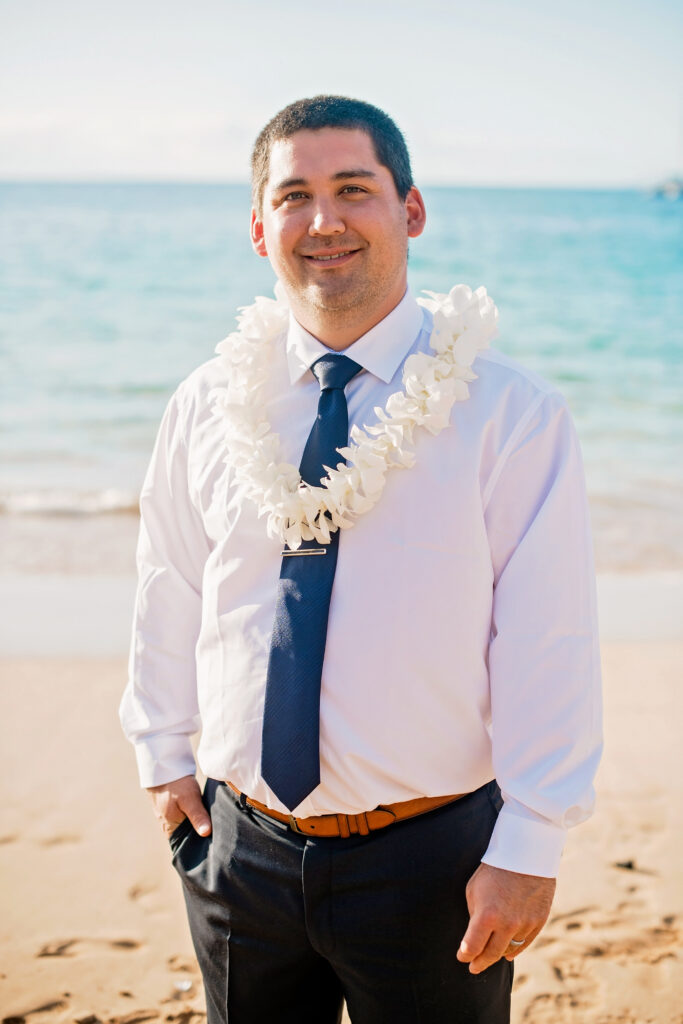 Groom in a white shirt and black pants with a white lei.