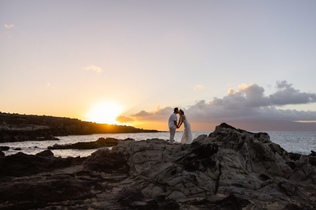 Ironwood Beach Kapalua wedding ceremony, couple kissing on lava rocks at Maui sunset

