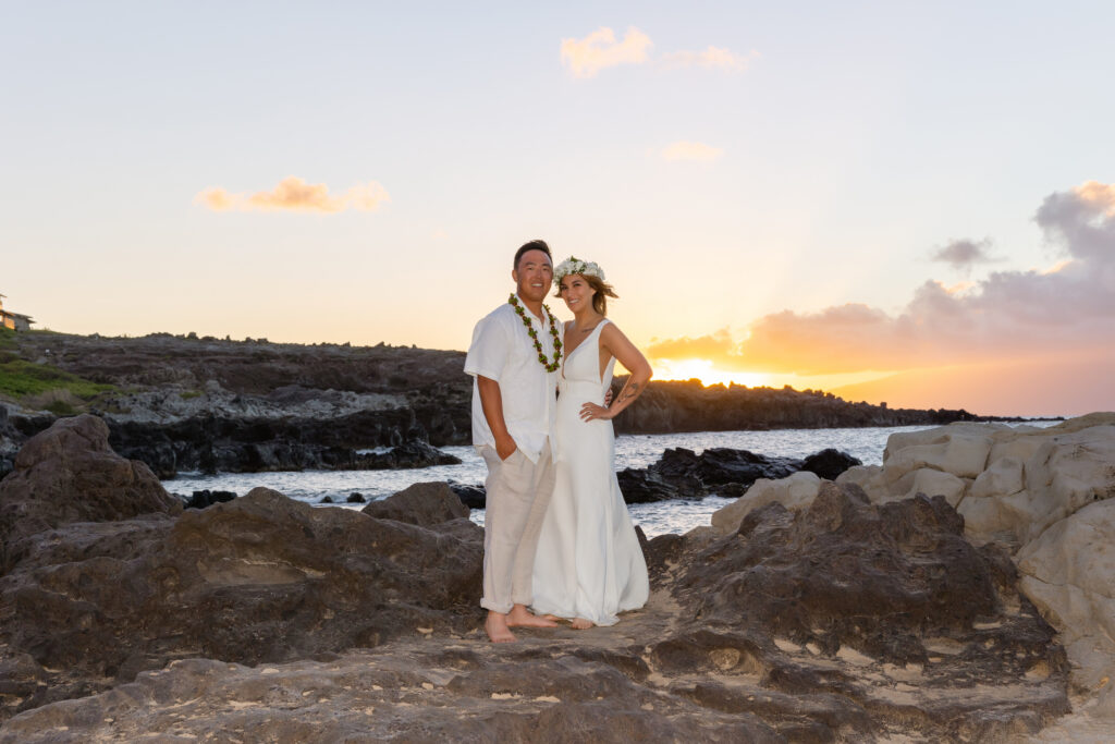 Newlyweds posing on lava rocks at sunset at Ironwood Beach, Maui 