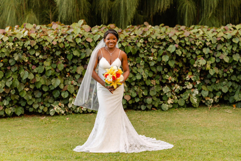Bride in lace gown holding a tropical bouquet before her Maui beach elopement ceremony