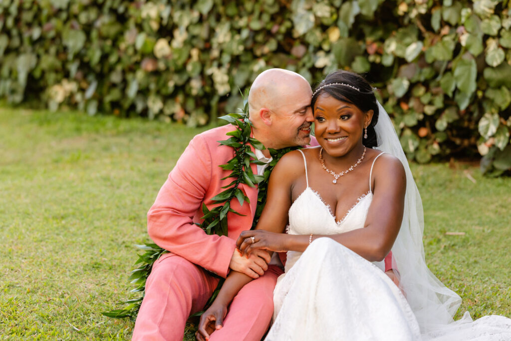 Bride and groom sitting together on the grass after their Maui beach elopement