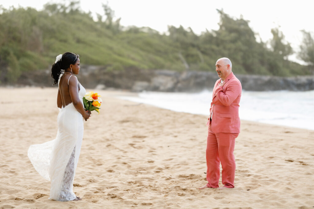 Bride holding bouquet and walking toward groom for their Maui beach elopement first look