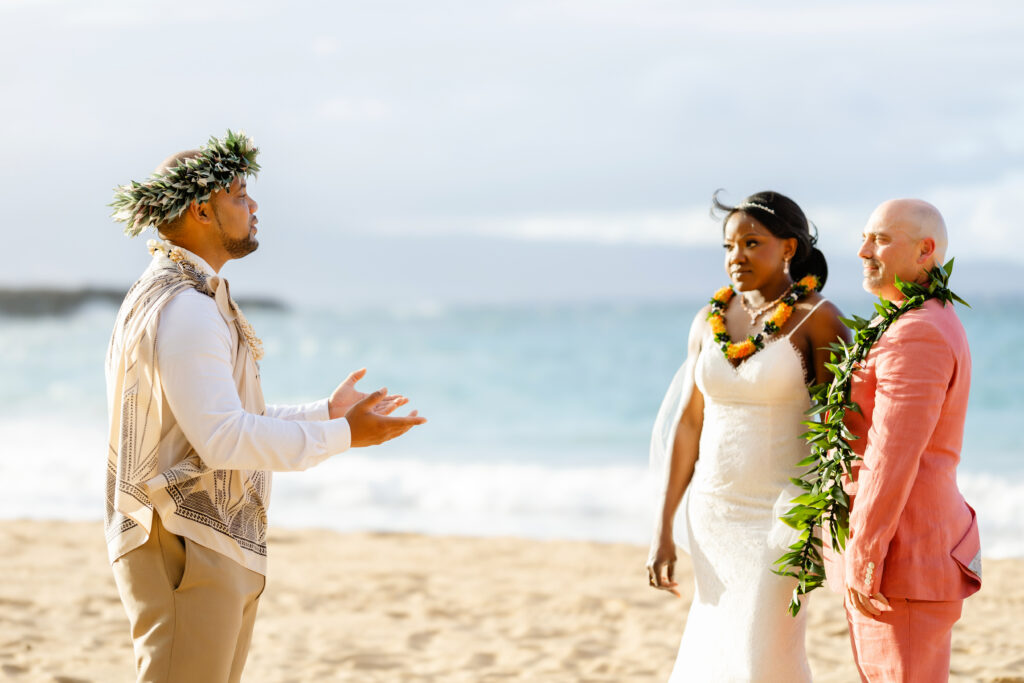 Hawaiian officiant speaking to bride and groom during their Maui beach elopement ceremony by the ocean