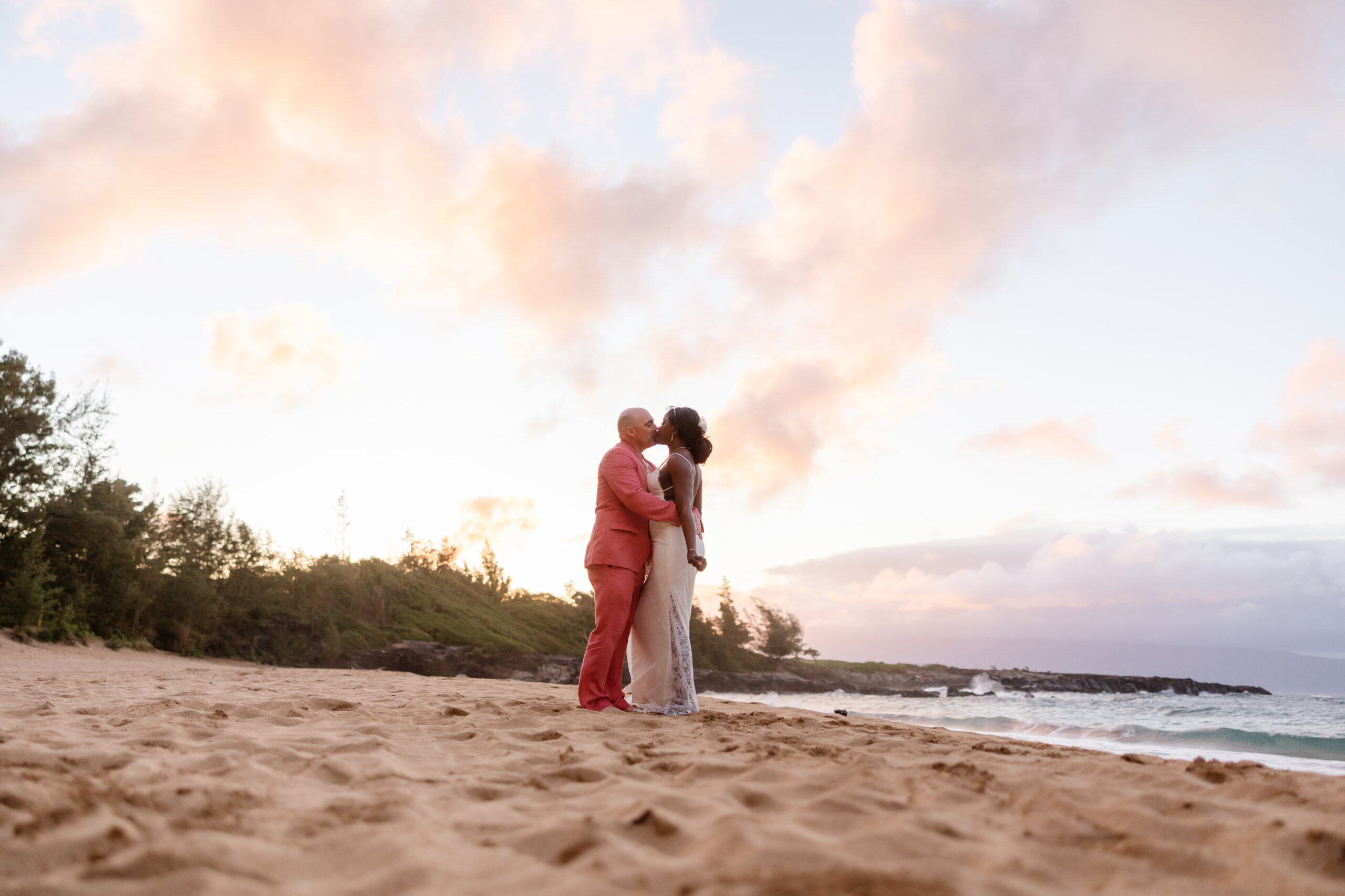 Couple kissing on the sand at sunset during their Maui beach elopement