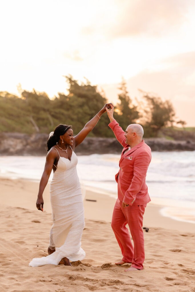 Groom twirling bride on the shoreline at their Maui beach elopement