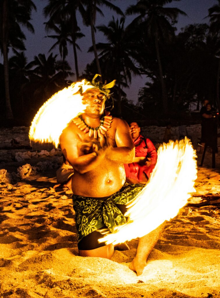 Fire performer entertaining guests during a beach luau experience in Maui