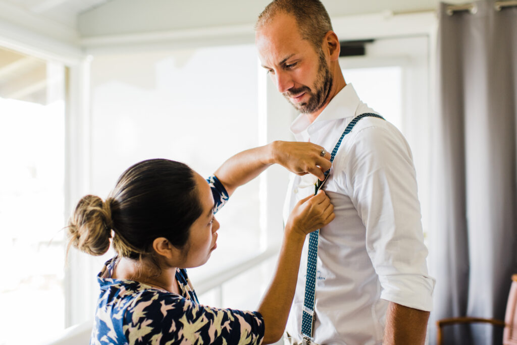 Planner helping pin a boutonniere onto the groom's shirt before their Maui elopement.