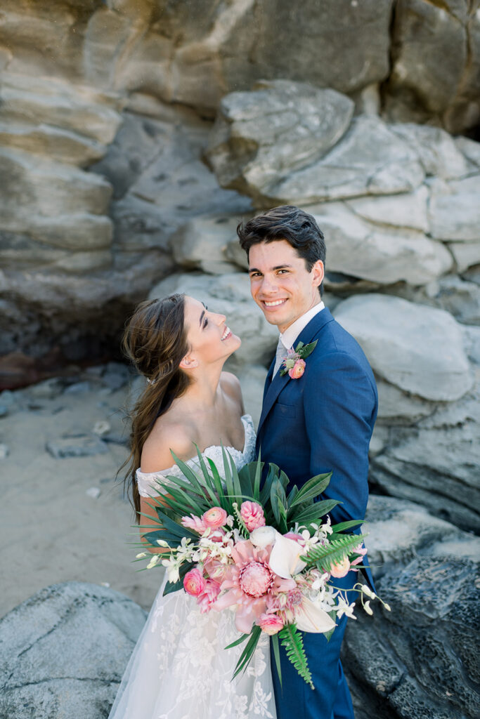 Bride and groom standing on Maui's rocky coastline during their destination wedding portraits.