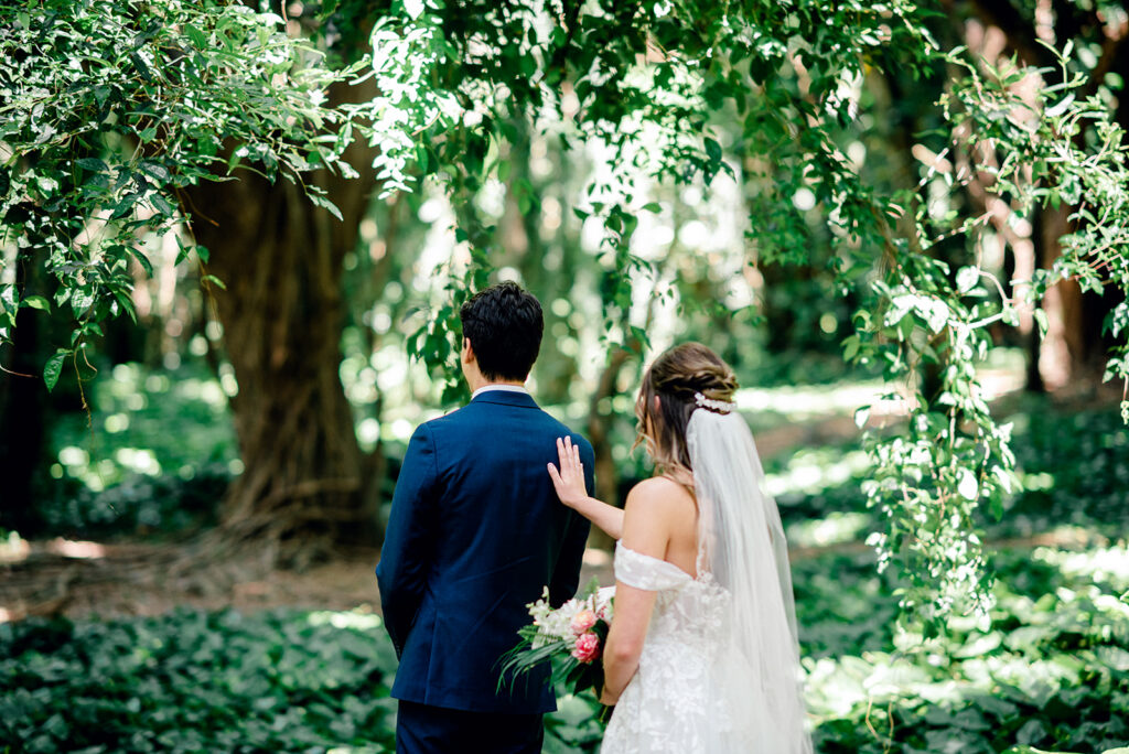 Bride approaching her groom during a first look in a tropical Maui forest setting.