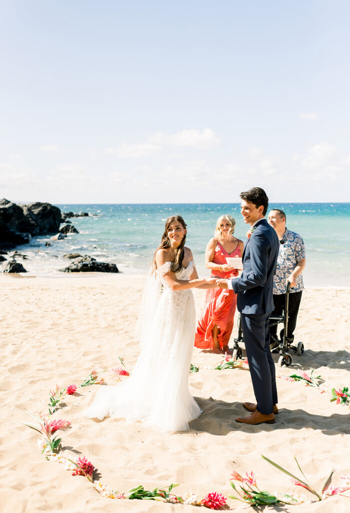 Couple exchanging vows during a Maui beach wedding ceremony while planning their wedding from another state.