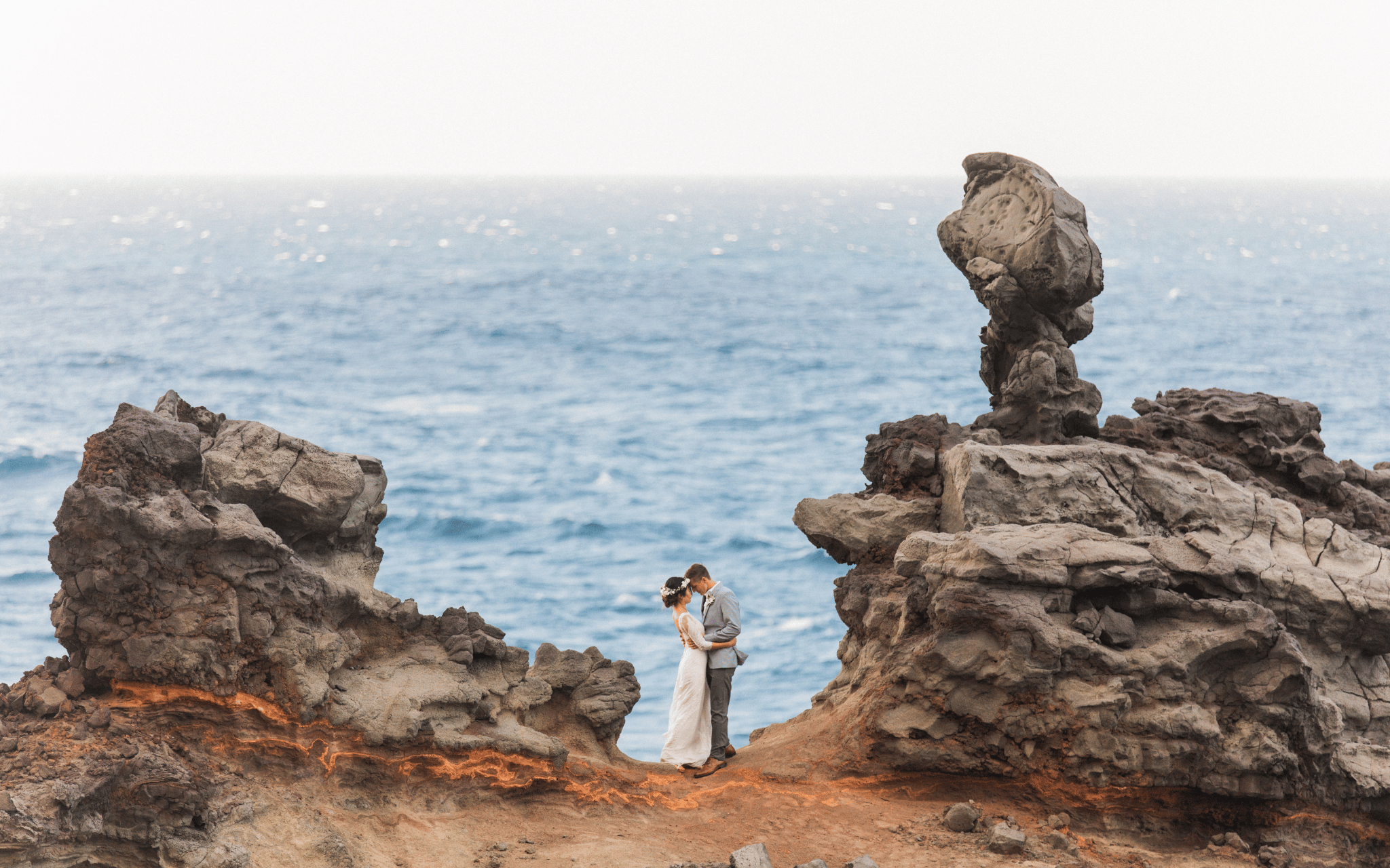 Couple sharing a quiet moment on dramatic ocean cliffs during their Maui elopement portraits.